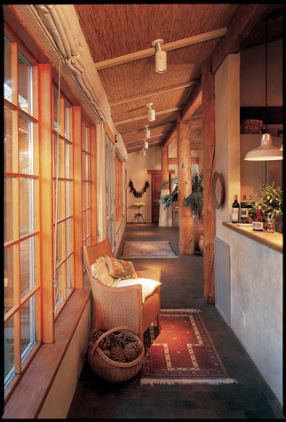 Bill built by hand the kiva-style fireplace in the bathroom, right, which keeps bathers toasty no matter what the weather. Sheets of reed fencing that the couple found at Montgomery Ward cover R-45 insulation in the ceiling; brick floors soak up and store solar heat. In the living area, this page, 60 linear feet of windows let the sunshine in.